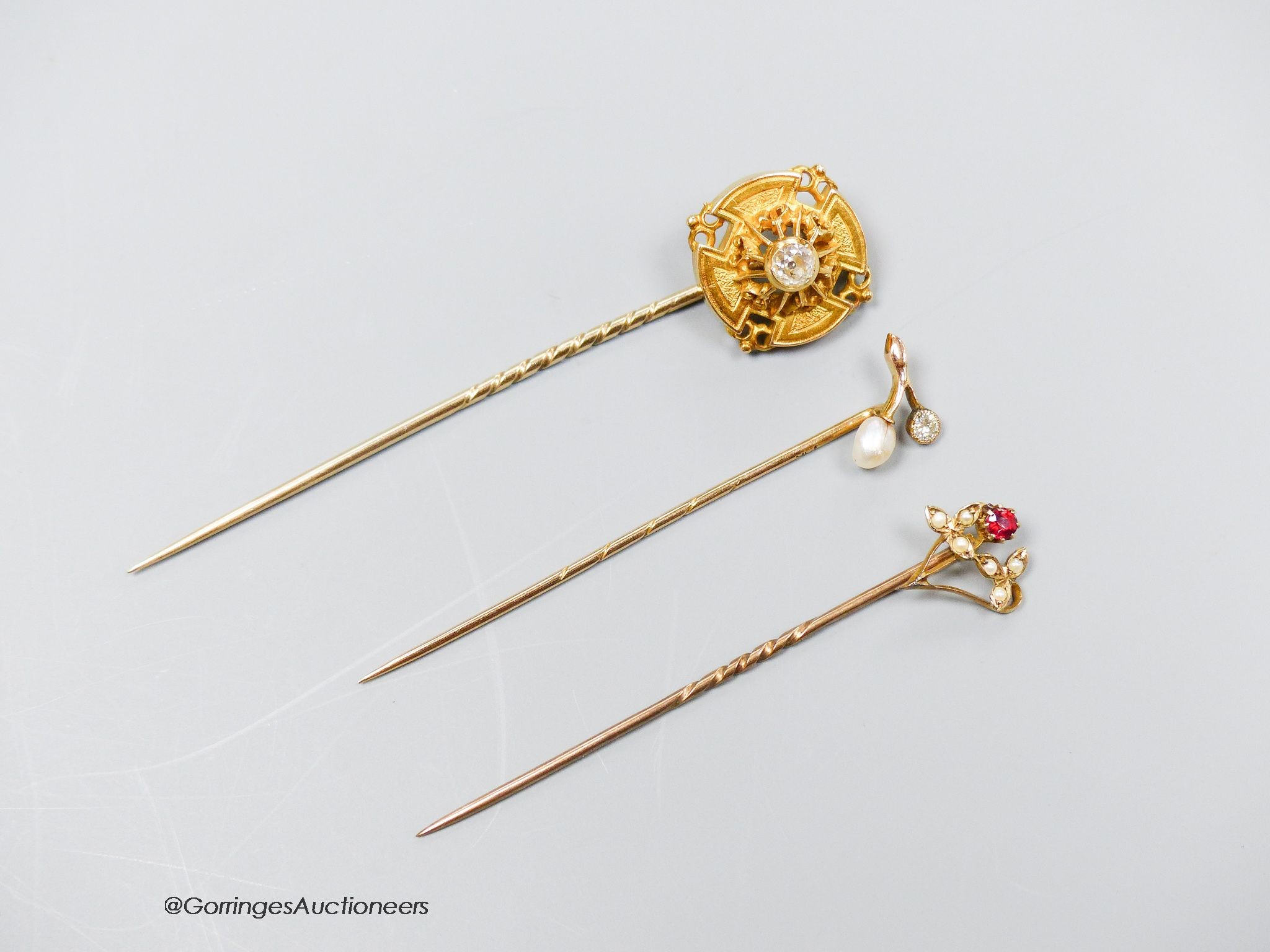 A Victorian diamond set gold target stickpin, another with pearl and diamond and a third with red stone and pearls.